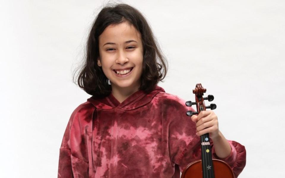 Child holding violin and smiling