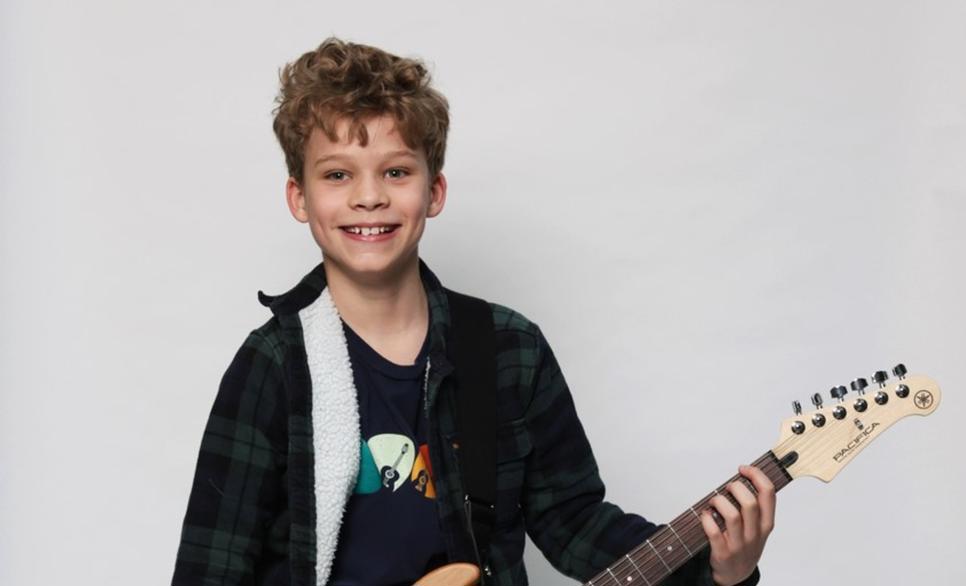 Child with electric guitar smiling