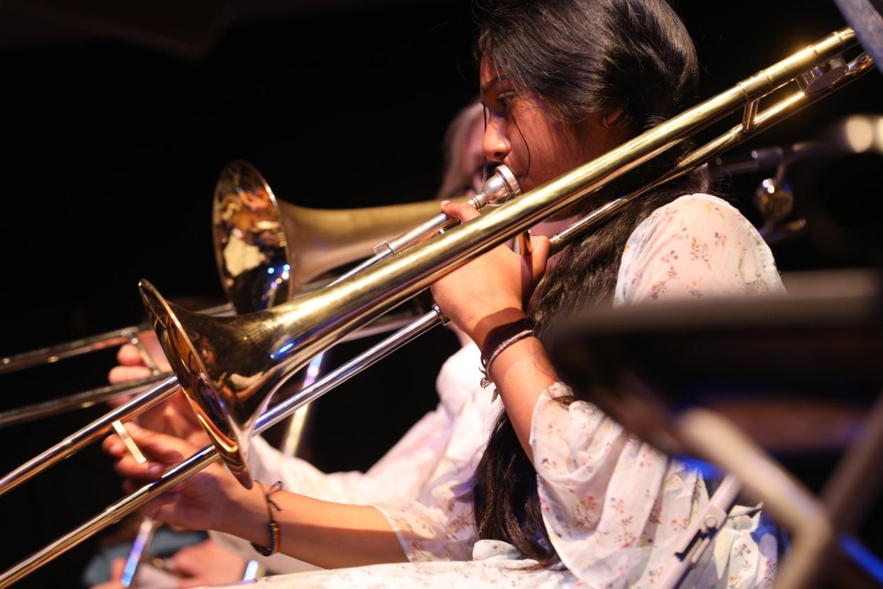 A portrait photo of a young girl playing trombone in a brass band.