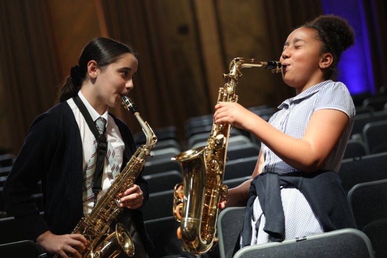 Photograph of two young saxophonists playing together